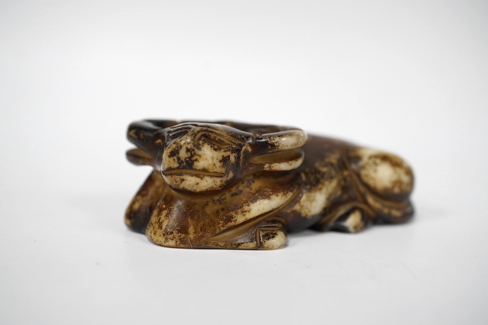 A Chinese pale green jade gourd pendant, a Chinese jade white and russet jade figure of a recumbent goat and a Chinese hardstone recumbent figure of an ox, largest 6cm wide (3)., Condition - good